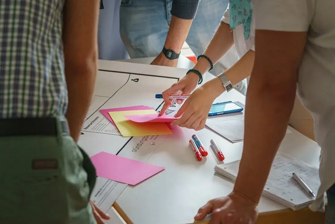 People gathered around a table, placing sticky notes on a sheet of paper.